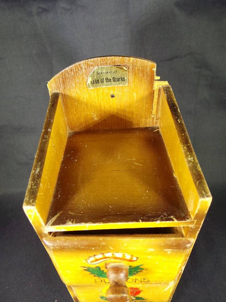 May include: A wooden box with three drawers, each with a different design. The top drawer has a wooden knob and the text "Souvenir of Lake of the Ozarks".