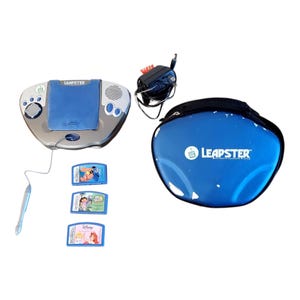 May include: A Leapster learning system with a blue and silver design, a stylus, and three game cartridges. Includes a blue carrying case with the Leapster logo and a black power adapter.