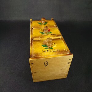 May include: Wooden box with three drawers for storing sewing supplies. The drawers are labeled "Buttons", "Needles & Pins", and "Needles".