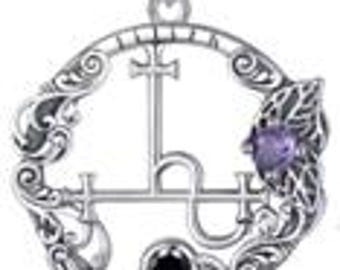 May include: A silver-toned pendant necklace featuring an ornate circular design with a central cross and stylized script. The pendant includes a black and a purple gemstone, and is suspended from a delicate chain.