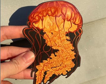 May include: A vibrant sticker featuring a detailed illustration of a jellyfish. The jellyfish has a reddish-orange bell and flowing tentacles in shades of orange and yellow, set against a black outline. The design is artistic and eye-catching.
