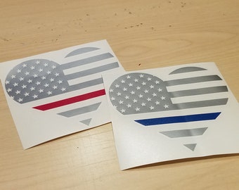 May include: Two heart-shaped decals with an American flag design. One decal has a red stripe across the bottom, and the other has a blue stripe across the bottom.