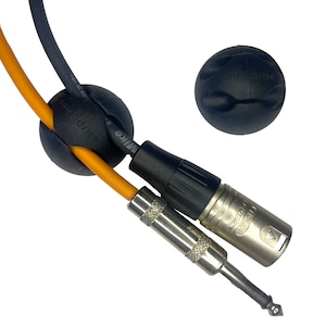 Puede incluir: Dos organizadores de cables negros con el texto "d'rise" en ellos. Un organizador está sujetando dos cables, uno negro y uno naranja. El otro organizador está separado. Un cable de micrófono plateado con un conector negro está conectado al organizador que sujeta los cables.