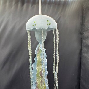 May include: A light blue felt jellyfish mobile with green and white yarn tentacles. The jellyfish has green glitter accents.