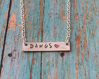 May include: Silver chain necklace with a silver bar pendant that says "DAWGS" with a red heart.