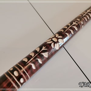 May include: A wooden walking stick with intricate white floral carvings. The stick is dark brown with a glossy finish. The carvings are detailed and delicate, creating a beautiful pattern.