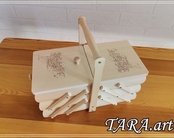 May include: A wooden sewing box with a hinged lid and a handle. The box is decorated with a laser-engraved tree design. The box has a folding design and is made of natural wood.