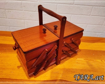 May include: A wooden sewing box with a hinged lid and a handle. The box has a brown finish and is decorated with a criss-cross pattern.