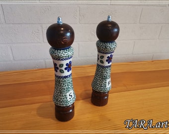 May include: A set of two ceramic salt and pepper shakers with a green and white speckled design. The shakers have a brown wooden top and base. The shakers are labeled "S" and "P".