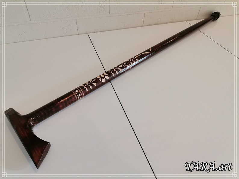 May include: A dark brown wooden walking stick with a carved floral design and a T-shaped handle.