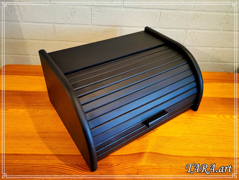May include: Black wooden bread box with a roll-top lid. The lid has a slatted design and a small handle.