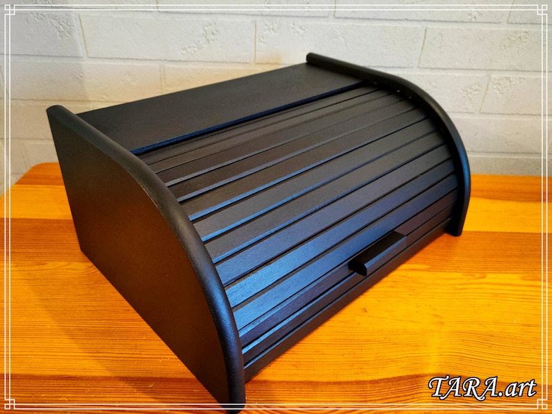 May include: Black wooden bread box with a roll-top lid. The lid has a slatted design and a small handle.