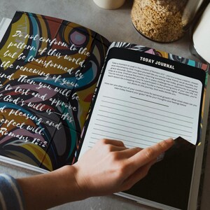 May include: Open journal with colourful abstract art on the cover and the text "Do not conform to the pattern of this world...Romans 12:2". The journal is open to a page with lined paper and the words "TODAY JOURNAL".