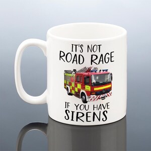 May include: White ceramic mug with the text "It's Not Road Rage If You Have Sirens" and a graphic of a red and yellow fire truck. The mug has a large handle and is suitable for hot or cold beverages.