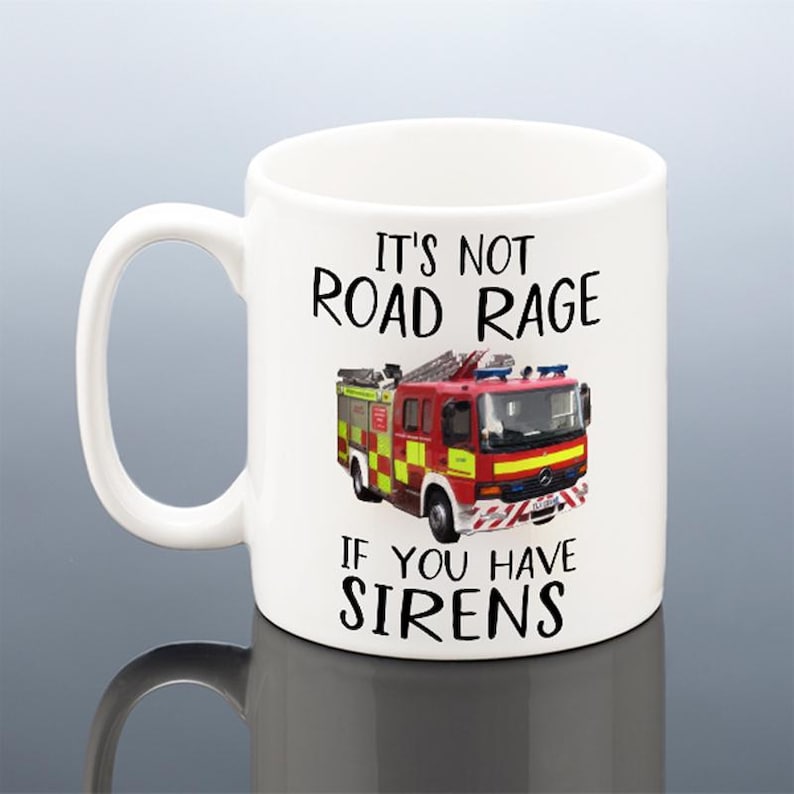 May include: White ceramic mug with the text "It's Not Road Rage If You Have Sirens" and a graphic of a red and yellow fire truck. The mug has a large handle and is suitable for hot or cold beverages.