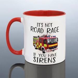 May include: White ceramic mug with a red interior and handle. The mug features a red fire truck graphic and the text "IT'S NOT ROAD RAGE IF YOU HAVE SIRENS" in black. The mug is designed for beverages.