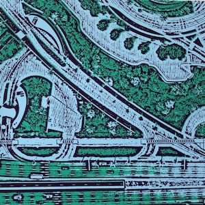 May include: An aerial view of a highway interchange with a large green park area in the background. The highway is divided into multiple lanes and has a complex network of ramps and bridges. The park is covered in lush green trees and shrubs.