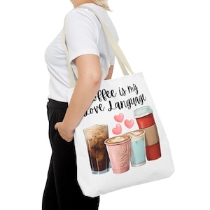May include: White canvas tote bag featuring the text "Coffee is my love language" and a graphic of four different coffee drinks with hearts.