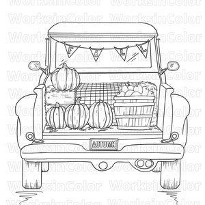 The back view of a pick up truck filled with pumpkins, hay bale and a basket of apples. The truck license plate says “autumn”.