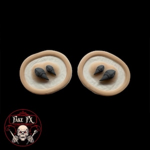 May include: Two small, round, beige silicone moulds with two black, pointy, 3D printed objects in each mould.