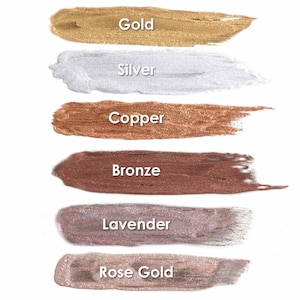 May include: Six metallic paint swatches in various colors, including gold, silver, copper, bronze, lavender, and rose gold. The swatches are arranged vertically on a white background.