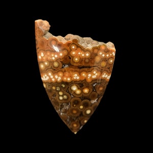 May include: A brown and white agate stone with a unique pattern of concentric circles. The stone is polished and has a smooth surface.