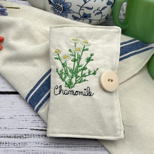 This is a tea wallet. It is made out of premium Muslim on the outside with a chamomile plant and the word chamomile on the outside front. It has six pockets to hold teabags sweetener, lens, cleaners, or anything else that this little wallet might be able to hold.