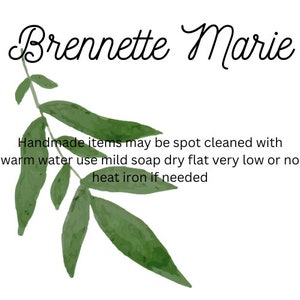 Op de afbeelding: Een witte achtergrond met de tekst "Brennette Marie" in een cursief lettertype. Onder de naam staat een groene aquarel illustratie van bladeren. De tekst onder de bladeren luidt: "Handgemaakte items kunnen worden schoongemaakt met warm water, milde zeep, plat drogen, zeer laag of geen hitte strijken indien nodig."