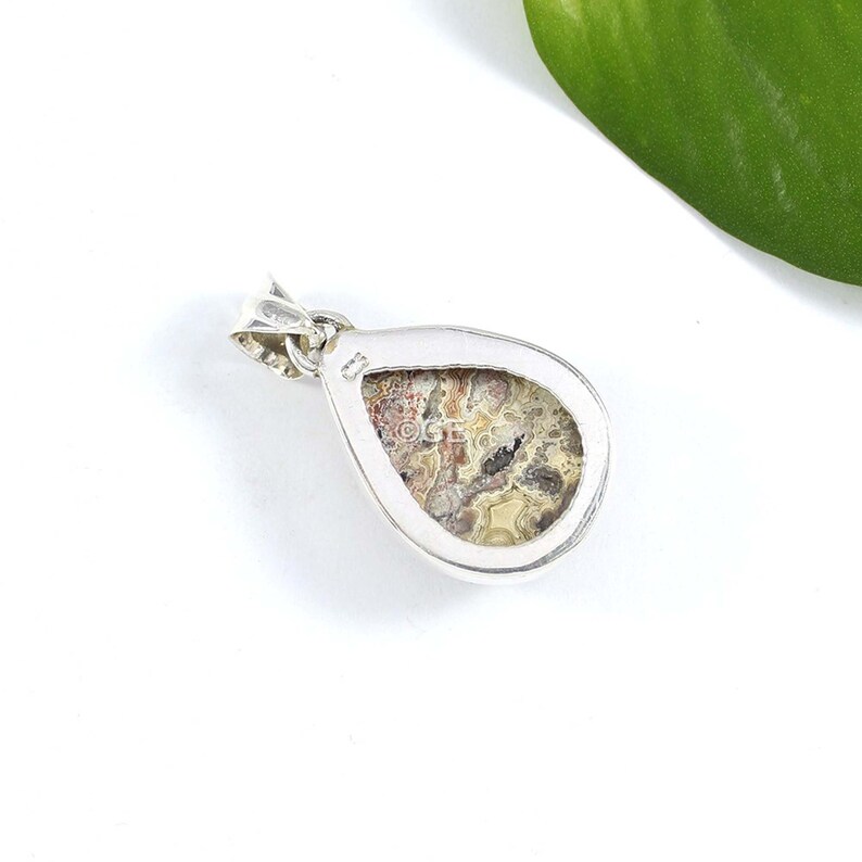 Puede incluir: Pendiente de plata con una piedra de &aacute;gata en forma de l&aacute;grima de color marr&oacute;n, blanco y gris.
