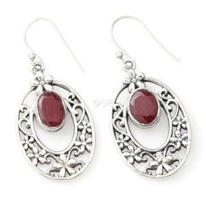 Könnte beinhalten: Silberne Ohrringe mit einem roten Edelstein, der in einem filigranen Design gefasst ist.
