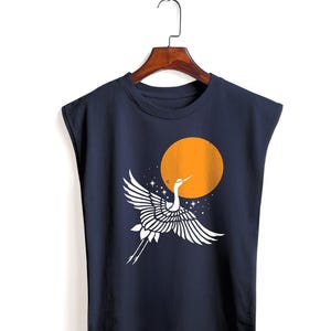 Op de afbeelding: Marineblauw mouwloos shirt met een wit kraanvogelontwerp tegen een oranje zon en een sterrenhemel. De kraanvogel heeft uitgespreide vleugels, wat een minimalistische, artistieke esthetiek creëert.