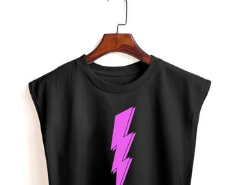 May include: Black crop top with a vibrant pink lightning bolt graphic. The sleeveless shirt is hanging on a wooden hanger against a white background. The lightning bolt design has a 3D effect.