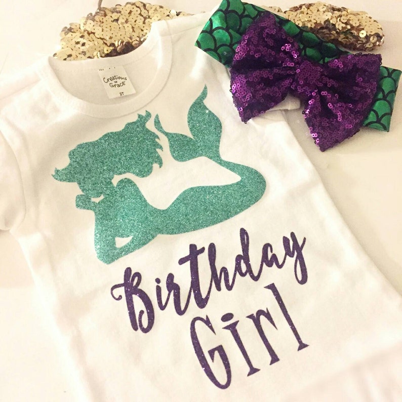 Puede incluir: Camiseta blanca con una sirena de purpurina verde y texto de purpurina morado que dice "Birthday Girl".