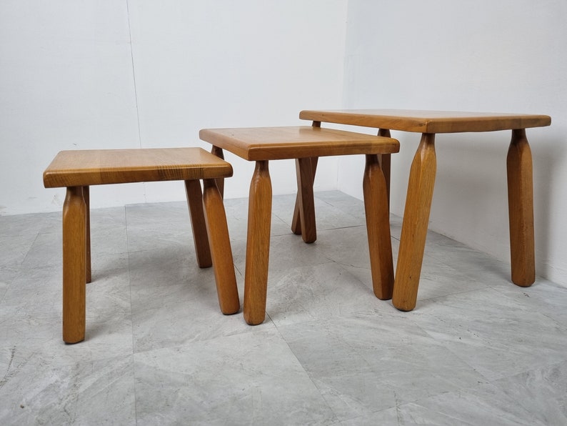 Puede incluir: Conjunto de tres mesas nido de madera con acabado natural. Las mesas son cuadradas y tienen cuatro patas cada una. Las patas est&aacute;n ligeramente acampanadas en la parte inferior.