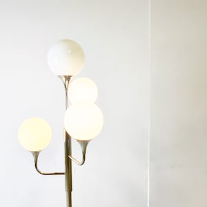 May include: A chrome floor lamp with four white globe-shaped shades. The lamp has a modern design with a branching structure.