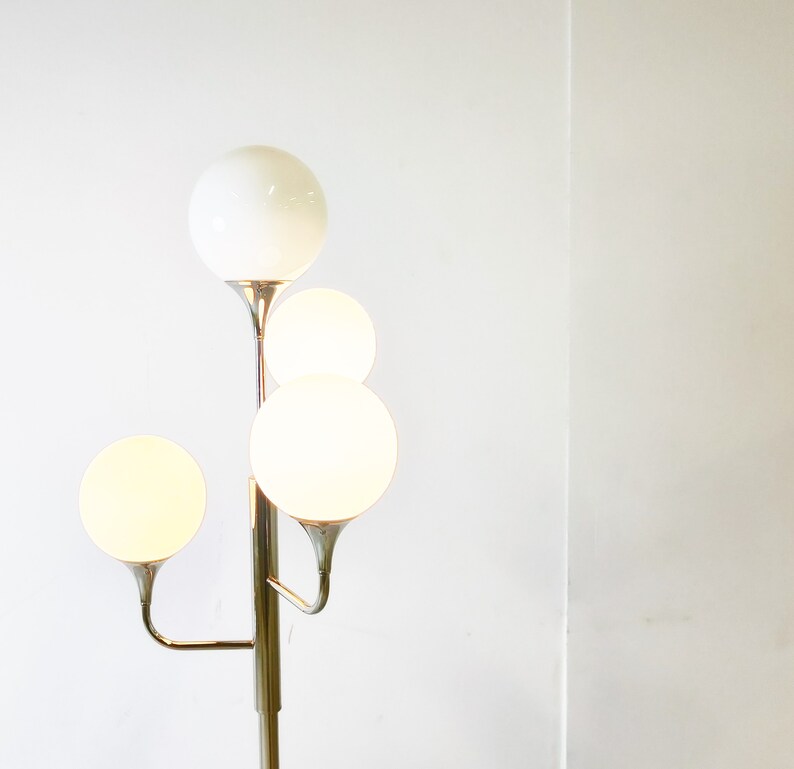 May include: A chrome floor lamp with four white globe-shaped shades. The lamp has a modern design with a branching structure.