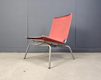 May include: A mid-century modern style chair with a red fabric seat and back. The chair has a silver metal frame and four angled legs. The design is minimalist and suitable for indoor or outdoor use.