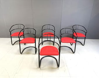 May include: Six black metal chairs with red fabric seats. The chairs are arranged in a row, with the backs of the chairs facing the viewer.