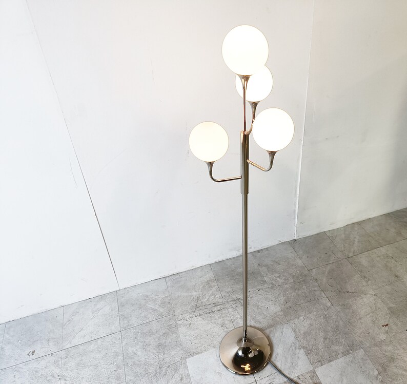 May include: A chrome floor lamp with five white globe-shaped shades. The lamp has a modern design with a central pole and branching arms.