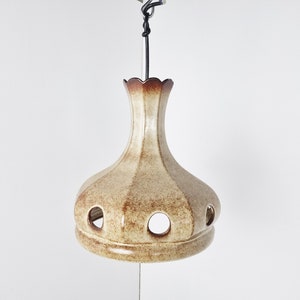 May include: A ceramic pendant light fixture with a brown and beige glaze. The light has a rounded, bulbous shape with a scalloped top and several circular cutouts.