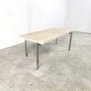 May include: A rectangular travertine dining table with a light beige colour and a brushed stainless steel base. The table has a simple, modern design.