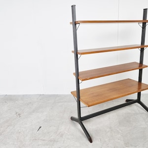 May include: A black metal shelving unit with four wooden shelves. The shelves are made of a light brown wood and the unit has a black metal base.