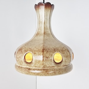 May include: A ceramic pendant light fixture with a brown and white speckled glaze. The light has a rounded, bulbous shape with several circular cutouts that allow light to shine through.