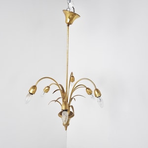 Pode incluir: Um candeeiro de teto de metal dourado com um design floral e seis lâmpadas. O candeeiro tem um caule longo e fino e braços curvos que se estendem para fora.