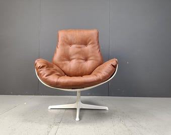 May include: A brown leather swivel chair with a white base. The chair has a rounded back and a comfortable seat.