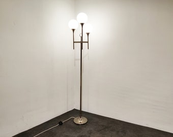 May include: A gold floor lamp with three white globe shades. The lamp has a long, slender stem and a round base.