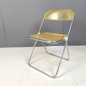 May include: A chrome folding chair with a translucent amber plastic seat and back.