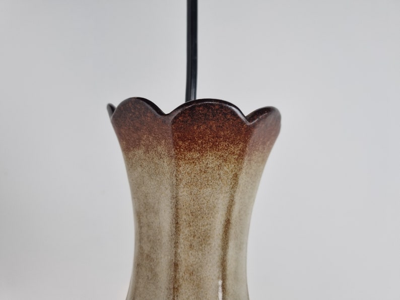 May include: A brown and beige ceramic vase with a scalloped rim. The vase has a speckled glaze and a gradient of color from brown to beige.