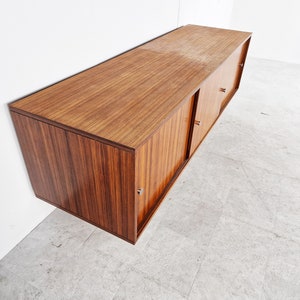 May include: A dark wood wall-mounted cabinet with sliding doors and silver handles. The cabinet has a sleek, modern design.