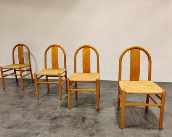 Puede incluir: Cuatro sillas de madera con asientos de caña trenzada. Las sillas tienen un respaldo curvo y son de madera marrón claro.